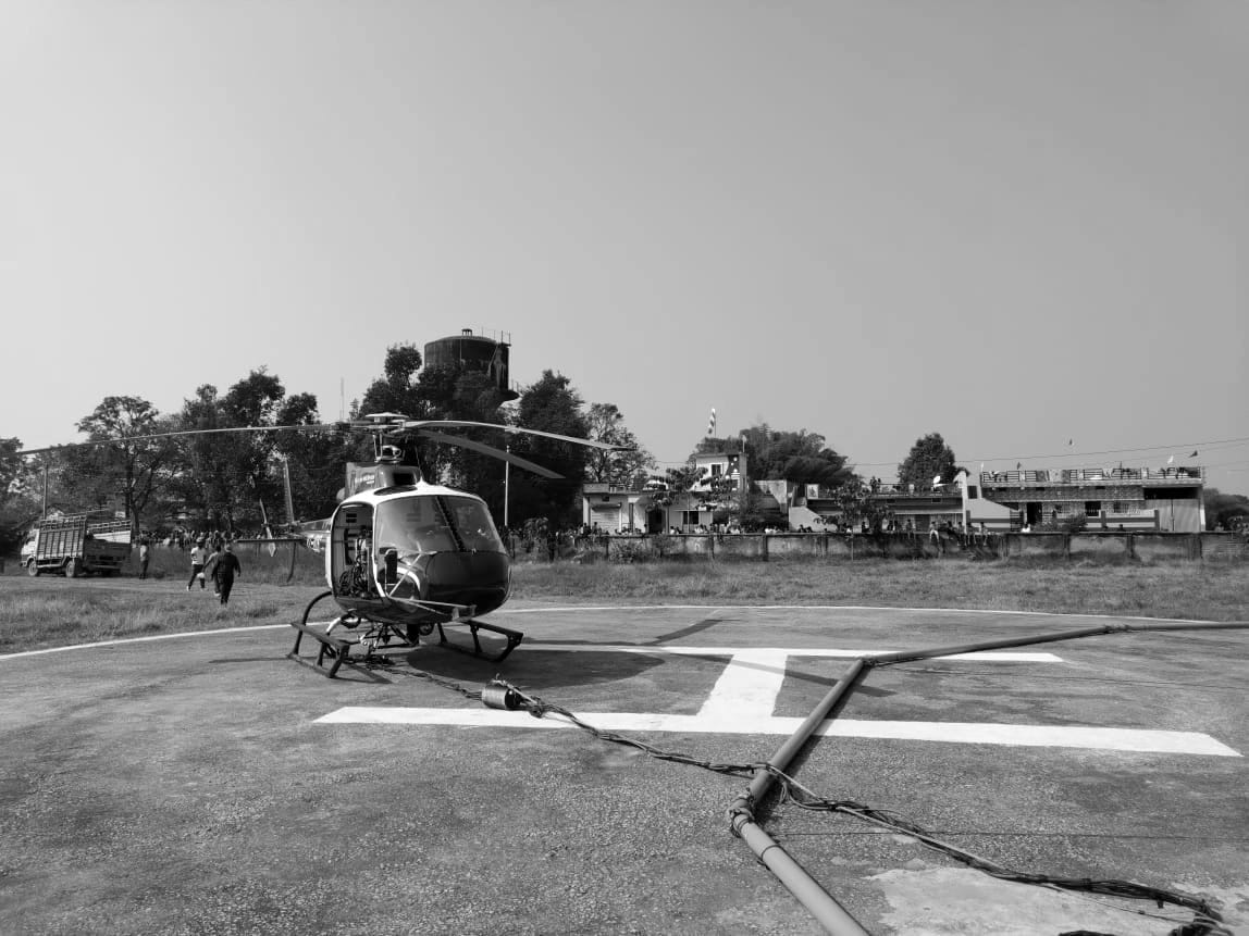 A helicopter on a concrete helipad with an external load line laid out across the pad in the foreground.